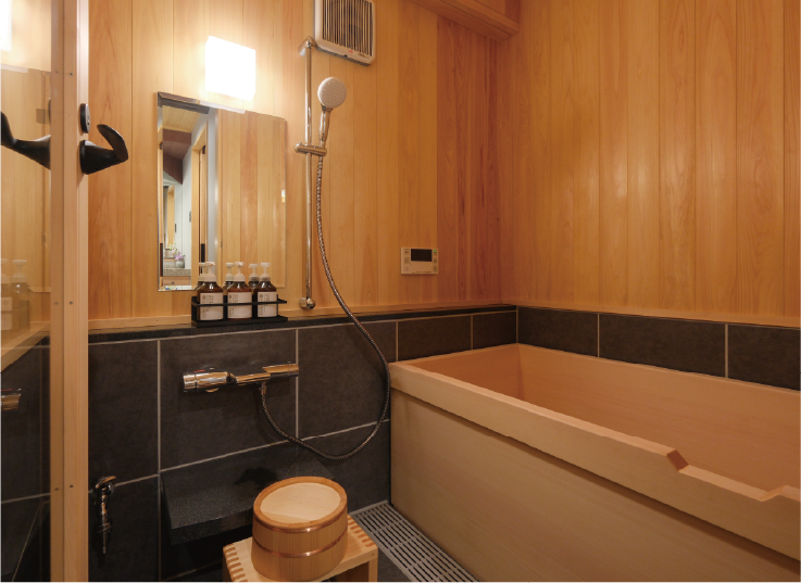 天然ヒノキを利用した浴槽や壁、桶、バスチェアがある浴室の写真